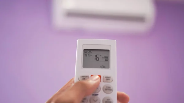Close up of hand turn on air conditioner with remote control