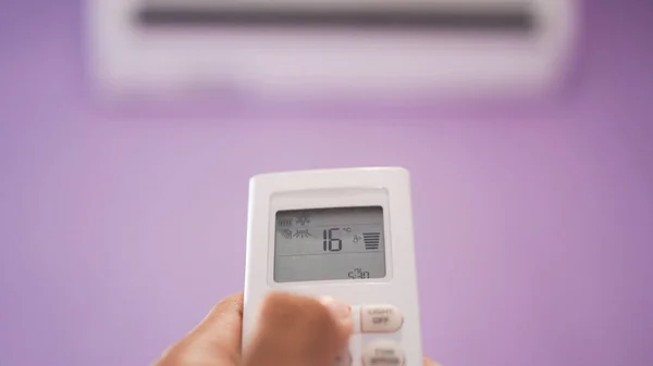 Close up of hand turn on air conditioner with remote control