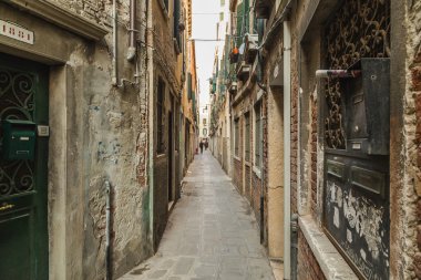 Venedik, İtalya - 13 Mart 2015: Venedik 'teki dar sokaklar boyunca eski binaların dışını gösteren bir manzara. İnsanlar görülebilir..