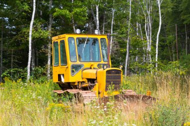 NOVA SCOTIA, CANADA - 27 Ağustos 2014: Bir tarlaya park edilmiş küçük parlak sarı bir traktör.