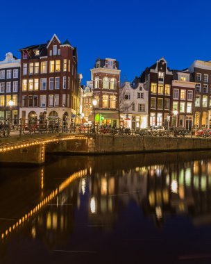 AMSTERDAM, NETHERLANDS - 16 Şubat 2016: geceleyin Amsterdam 'daki Keizersgracht kanalı boyunca bir manzara. Binalar, köprüler, arabalar ve motorlar görülebilir.