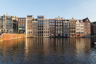 AMSTERDAM, NETHERLANDS - 17 Şubat 2016: Amsterdam 'daki Damrak boyunca eski binalar. İnsanlar görülebilir..