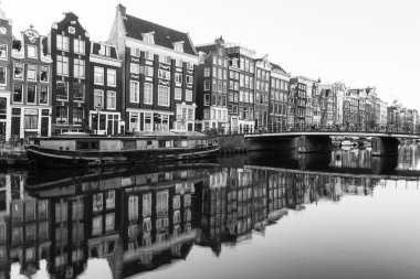 Amsterdam, Hollanda - 16 Şubat 2016: Amsterdam Kanalları boyunca binaların ve teknelerin manzarası. Yansımalar suda görülebilir.
