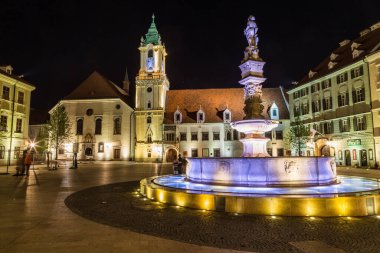 BRATISLAVA, SLOVAKIA - 29 Nisan 2016: Bratislava, Slovakya 'daki Old Town Hall, gece yarısı ön planda Maximilians Çeşmesi ile birlikte. İnsanlar görülebilir..