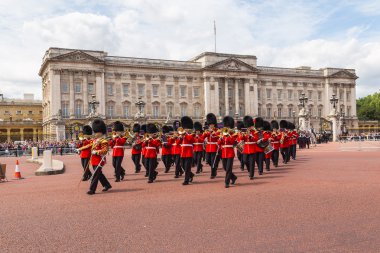 LONDON, İngiltere - 28 Haziran 2016: Yazın Buckingham Sarayı 'nda düzenlenen Muhafız Değişim Töreni sırasında Alay Grubu' ndan müzik desteği. Askerler kırmızı ceketler ve ayı postu şapkaları giyerken görülebilir.
