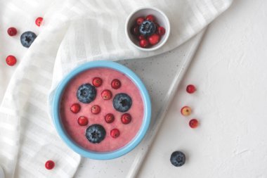 Vejetaryen taze yaban mersinli meyve püresi beyaz masa örtüsü ve kesim tahtası. Sağlıklı yemek, en iyi manzara.