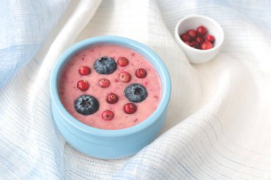 Beyaz ve mavi masa örtüsü üzerinde yabanmersinli taze yaban mersini püresi. Üst manzara, sağlıklı gıda konsepti..