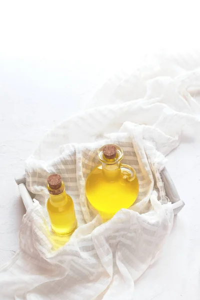 Two raw vegetable oils in a beautiful glass bottle on a white tablecloth and a wooden tray and background, cedar and sunflower. Top view, copy space. Healthy vegetable fats