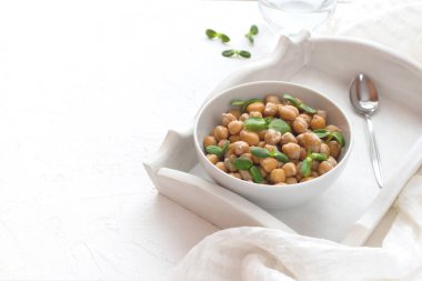 Tepside bir kasede ve beyaz desenli arka planda ayçiçeği mikroyeşil lahanalı nohut pişirdim. Ön görünüm, boşluğu kopyala.