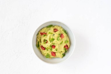Beyaz arka planda bir kasede çiğ guacamole. Sağlıklı yeme kavramı.