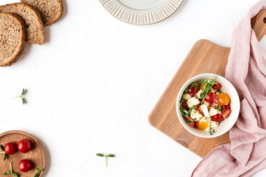 Taze mozarella soslu caprese salatası, ahşap kesim tahtasındaki bir tabakta domates ve mikroyeşiller, dilimler, pembe peçete, üst manzara, kopyalama alanı. Akdeniz, İtalyan mutfağı, vejetaryen tarifi..