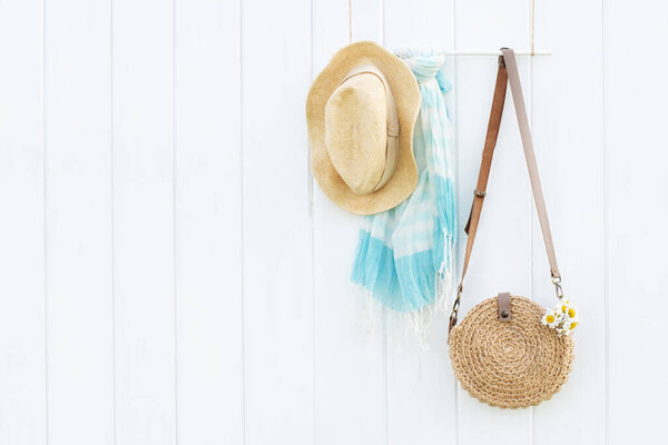 Beautiful handmade jute bag, summer scarf and hat on white wooden wall, boho style and minimalism concept. Place for text.