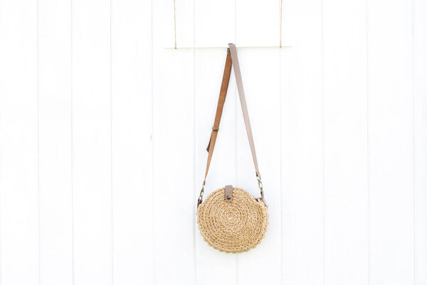 Beautiful handmade jute bag on white wooden wall, boho style, summer vacation concept. Place for text.