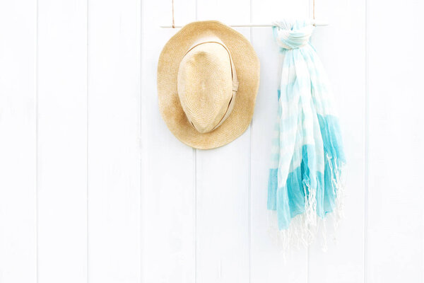 Beautiful summer scarf and hat on white wooden wall, boho style and minimalism concept. Place for text.