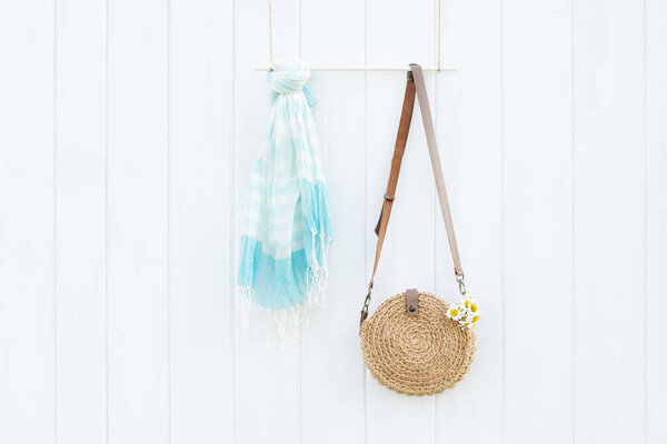 Beautiful handmade jute bag, summer scarf on white wooden wall, boho style and minimalism concept. Place for text.