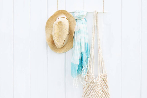 Beautiful summer scarf, hat and eco bag on white wooden wall, boho style and minimalism concept. Place for text.