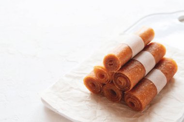 Çiğ elma şekeri, seramik mutfak tahtasında meyveli pastil ve beyaz arka plan. Sağlıklı tatlılar. Sağlıklı tatlılar, kopyalama alanı.