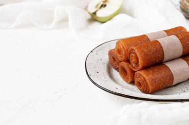 Seramik tabakta çiğ elmalı pastil ve beyaz arka plan. Sağlıklı tatlılar. Düz yat, boşluğu kopyala.