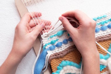 Beyaz arka planda asılı duran kadın el yapımı duvar örüyor. Düzlük, hobi konsepti.