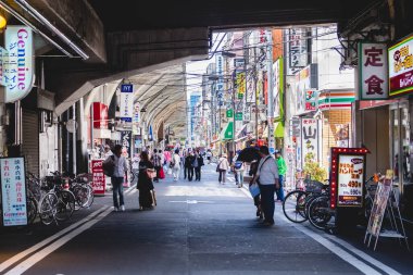 Tokyo, Japonya: Şehir merkezindeki demiryolunun yanındaki insanlar, mağazalar, işaretler ve teller