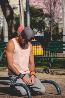 Formda ve yakışıklı bir adam güneşli bir yaz gününde bir sokak idman parkında spor yaparken dinleniyor.