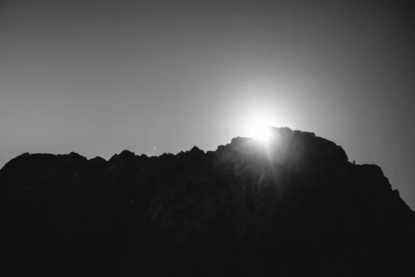 Sunrise in the mountains silhouettes and little half moon (in black and white)