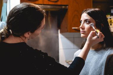 Bir makyöz güzel ve genç bir esmer modeli fotoşop için hazırlıyor.