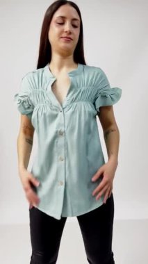 Beyaz stüdyoda şık kıyafetler sergileyen zarif esmer manken.