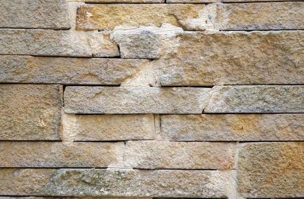 A fence made of beige stones fastened by cement as background — Stock Photo, Image