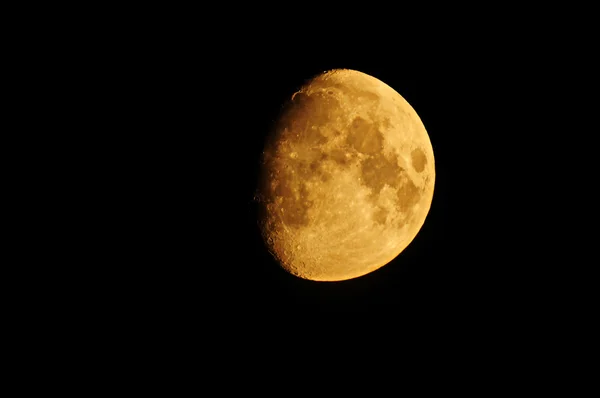 Yellow large Waxing Moon against a black sky
