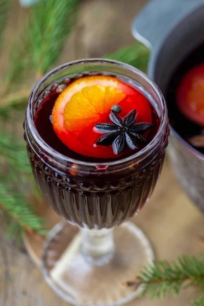 Hot mulled wine in a glass. Beautiful Christmas drink. Hot autumn mulled wine on a wooden table. Delicious wine and fruit drink.Merry Christmas 2021