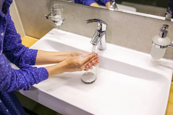 The girl washes her hands in soap. Liquid soap. A drop of soap. Wash your hands during a pandemic. Clean hands. Washbasin with soap and water. Washes hands with liquid soap. Beautiful manicure with soap. Clean hands. Wash