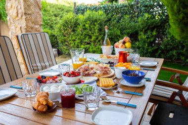 Terasta yemekli bir masa. Büyük bir aile için bir yemek masası. Bir parti. Yaz terasında bir akşam yemeği. Sokakta bir doğum günü.