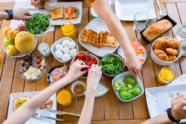 Food on the table. Breakfast on the terrace with the family. Friends are eating at the table. World Food Day Healthy Food Table Top View Party Birthday Lots of food for breakfast. Buffet. Avocado, salmon, cheese, cherry. Family eats