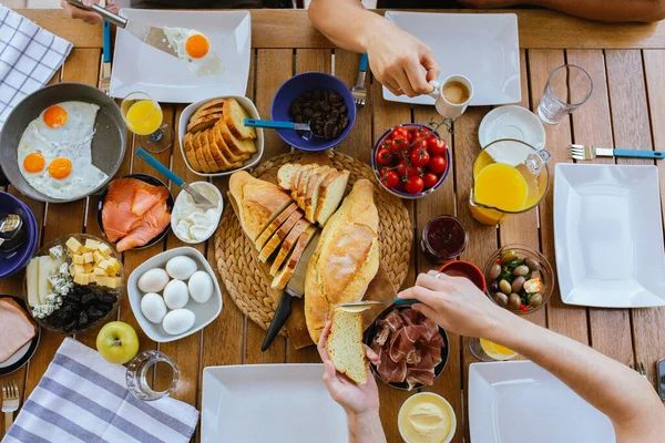 Beautiful breakfasts on the table top view. Large table with food top view. Table with food and people\'s hands. People have breakfast at the table top view.Beautiful breakfast for a large family. Breakfast constructor. Dinner