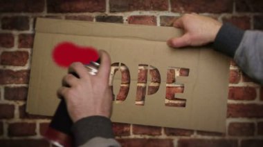 Umut spreyi tuğla duvara kırmızı yazı yazmış. İyimser duygu ve rüya graffiti sanatı konsepti. Şehir soyut sanat eserleri. Elinde yazı şablonuyla hava fırçası boyası.