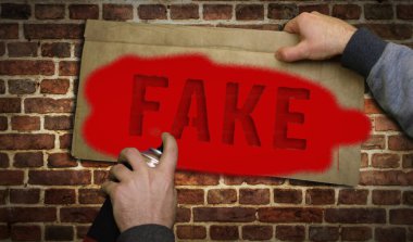 Tuğla duvara sahte sprey boya. Graffiti sanat konsepti yalan ve yanlış haber işareti. Şehir soyut sanat eserleri. Elinde işaret şablonuyla hava fırçası boyası.