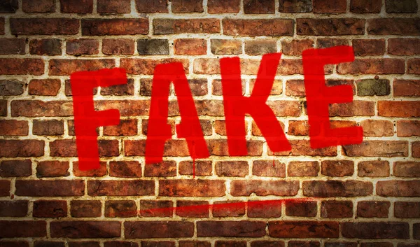 Fake spray painted on the brick wall. Graffiti art concept of lie and false news sign. Urban abstract artwork. Airbrush paint with sign template in hand.