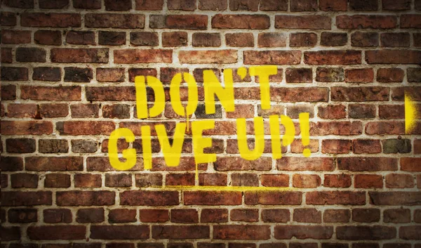 Don\'t give up sign spray painted on the brick wall. Graffiti art concept positive motivation and perseverance. Urban abstract artwork. Airbrush paint with template in hand.