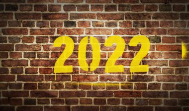 Tuğla duvara 2022 senelik işaret spreyi boyanmış. Graffiti sanat konsepti ikonu. Şehir soyut sanat eserleri. Elinde şablonla hava fırçası boyası.