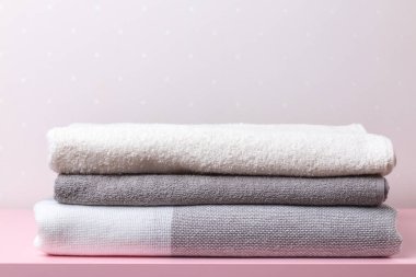 Bir yığın tekstil - bir masanın üzerindeki battaniye ve havlular bir ışık duvarının arka planına karşı.