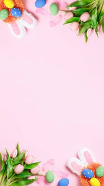 Paskalya yumurtaları, laleler, pembe arka planda tavşan kulakları. Fotokopi alanı düzleştirilmiş tebrik kartı.