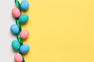 Paskalya renkli yumurtalar sarı ve gri arka planda sıralanır. Kopyalama alanı olan tebrik kartı.