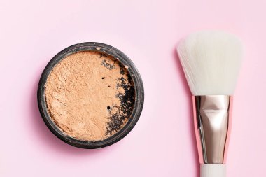 Kozmetik tozu, yüz makyajı için açık bir kavanozda pembe bir arka planda yüz fırçası..