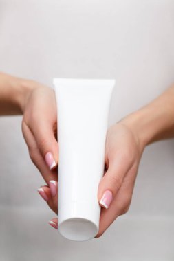 Genç bir kız elinde kozmetik ürünle bir tüp tutuyor. Cilt bakımı konsepti, gençlik ve cildin esnekliği.