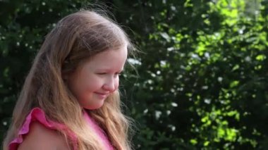 Rüzgarda süzülen uzun saçları olan sevimli, sevimli, küçük bir kız. Dışarıda, bahçede yakın plan bir çocuk..