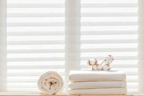 White linens bed linen sheets with a cotton branch and a terry towel against the background of the window. Natural composition.