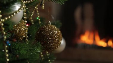 Noel ağacını şöminedeki yanan ateşin arka planına karşı süsleyen dönen bir top..