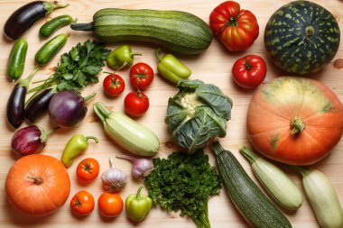 Tahta bir masanın üzerinde birçok farklı sebze ve otlar var. Hasat et. Üst görünüm düzlüğü