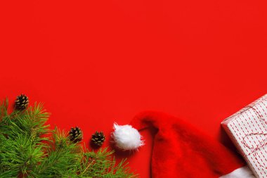 Hediye kutusundan Noel kompozisyonu, ladin dalları, kırmızı arka planda Noel Baba şapkaları. Düz görünüm kopyalama alanı
